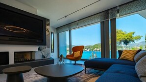 Un salón moderno con un televisor grande, una chimenea, un sofá y vista al mar.