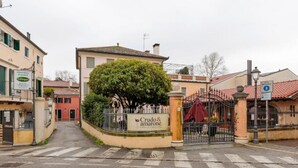 Une entrée fermée par un portail mène à un bâtiment sur lequel on peut lire l’inscription « Crudo & Amarone ».