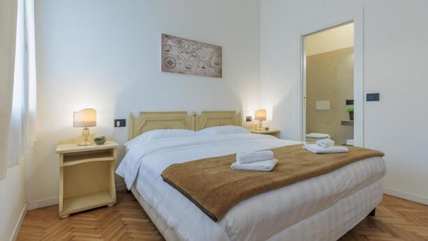 Une chambre à coucher bien rangée, avec un lit, des tables de chevet et une carte accrochée au mur.
