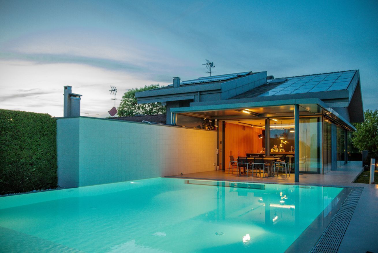 Ein modernes Haus mit Schwimmbad, Essbereich und einem großen Glasfenster, das zum Innenraum führt.