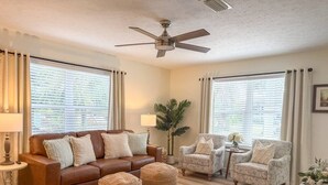 A living room with a brown leather sofa, two patterned armchairs, a coffee table, and a striped rug. - 8th At The Bay, New Listing (Port St. Joe)