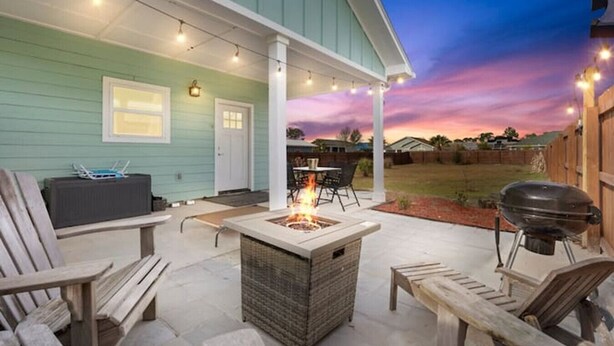 Un patio techado con una chimenea, mobiliario exterior y una parrilla.