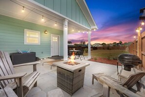 A covered patio with a fire pit, outdoor seating, and a barbecue grill. - All to Shell at the Beach (Port St. Joe)