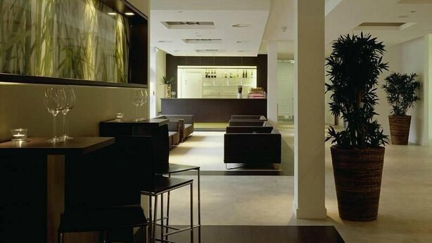Eine moderne Hotelhalle mit Barbereich, Sitzgelegenheiten und einer großen Pflanze in einem Topf.