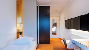 Ein modernes Hotelzimmer mit Bett, Schreibtisch und Spiegel.