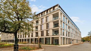Un immeuble à plusieurs étages doté d’une architecture moderne, caractérisé par de grandes fenêtres et des balcons.