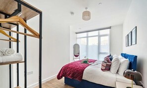 Ein Schlafzimmer mit einem Bett, einem Holzschrank, einem Spiegel und einem Fenster.