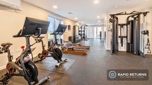 A gym with cardio machines, weightlifting equipment, and a mirrored wall.