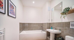 A modern bathroom with a bathtub, sink, and toilet. - Modern 2BR Apartment w/ Balcony, Parking, WiFi (Walton-on-Thames)