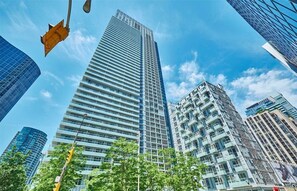 A modern high-rise building with a grid-like facade, surrounded by other tall buildings and trees. - Move in Ready RogersCenter CN Tower 2B2B City Lakeview &Free Parking (Toronto)