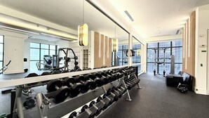 Ett modernt gym med utrustning för styrketräning, speglar och stora fönster.