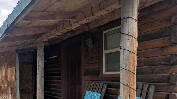 Une cabane en rondins avec une véranda, une porte et une fenêtre.