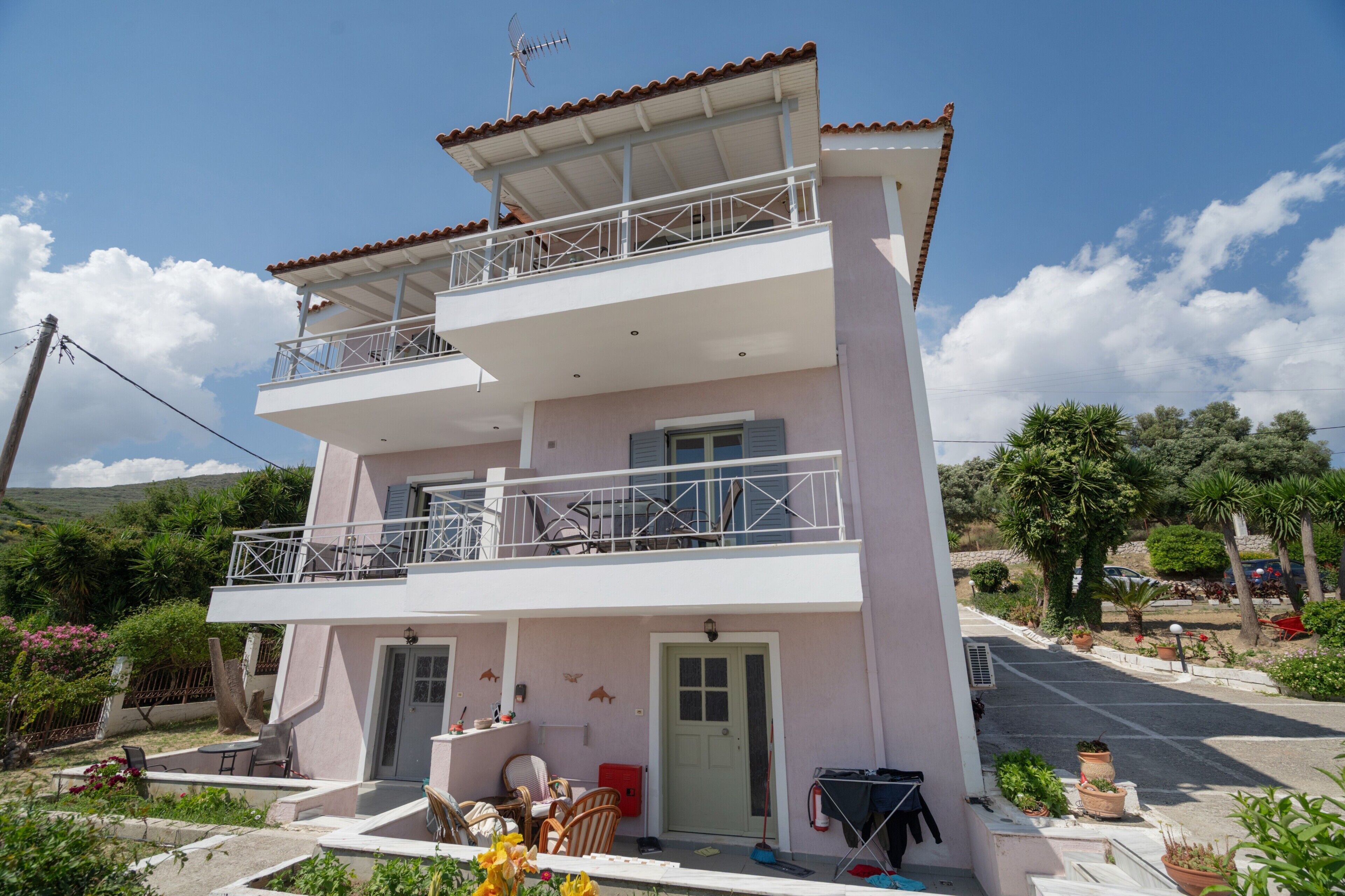 A two-story building with a balcony, a door, and a small outdoor seating area.