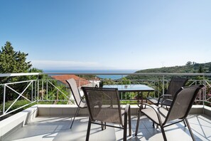 En terrasse med et bord og stole, med udsigt over et kystlandskab.