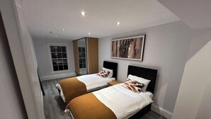 A modern hotel room with two beds, a large window, and a painting on the wall. - Apartment - Sleeps 6 & Near Station (Bedford)