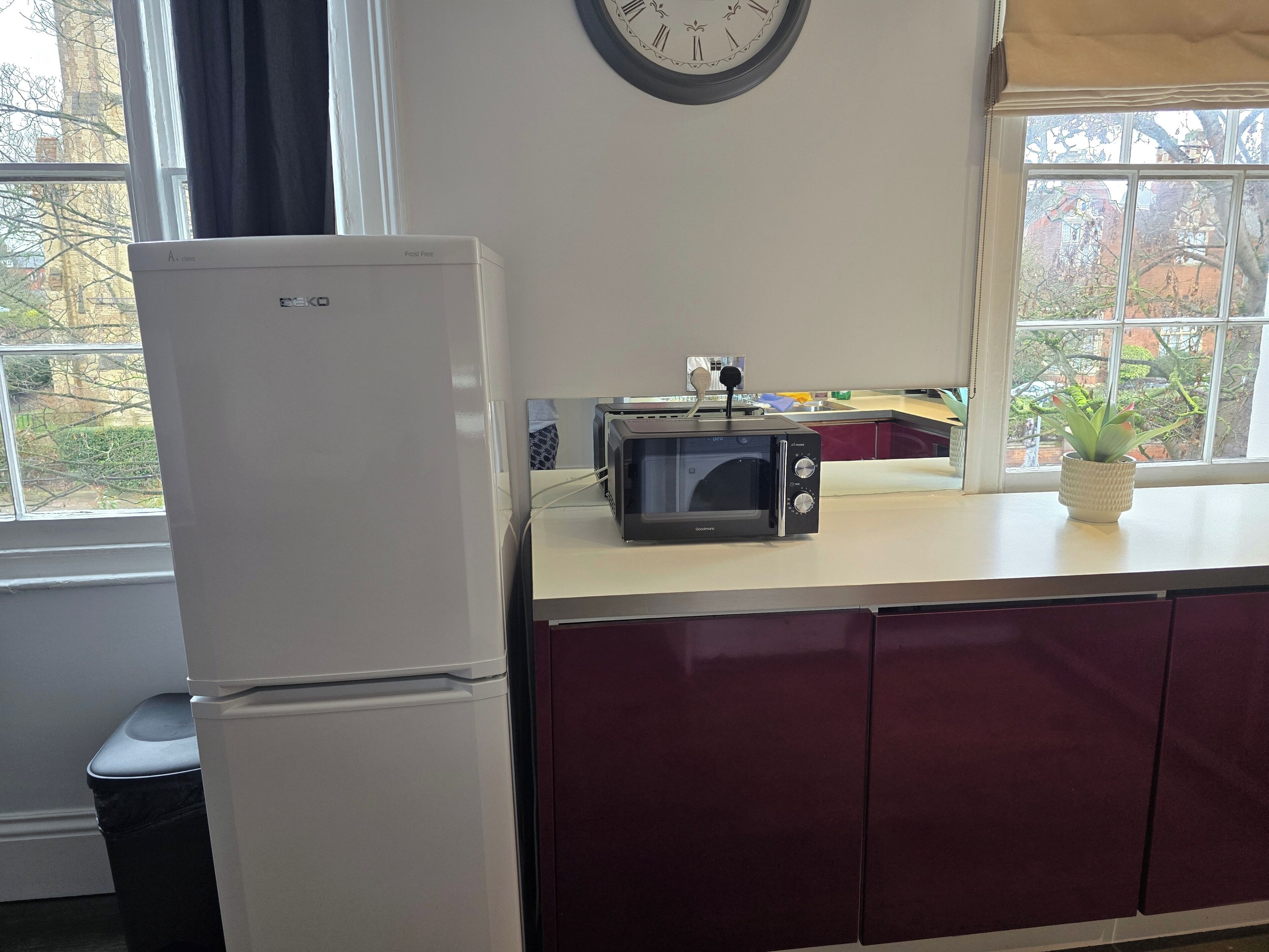 A kitchen with a white refrigerator, a black toaster, and a clock on the wall.