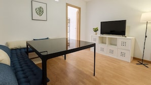 A modern living room with a sofa, a dining table, a TV on a white cabinet, and a floor lamp. - Corporate or Formative Lodging 4 rooms / 6 beds (Coslada)