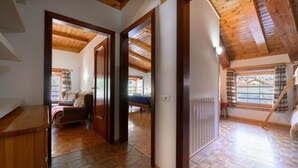 A spacious loft bedroom with a sloped ceiling, wooden beams, a large window with curtains, and a view of the outside. - Holiday Home 'La Casa Di Nonno Giulio' with Mountain View and Wi-Fi (Roncone)