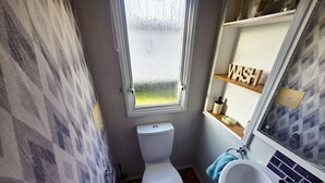 Ein kleines Badezimmer mit Toilette, Waschbecken und Fenster.