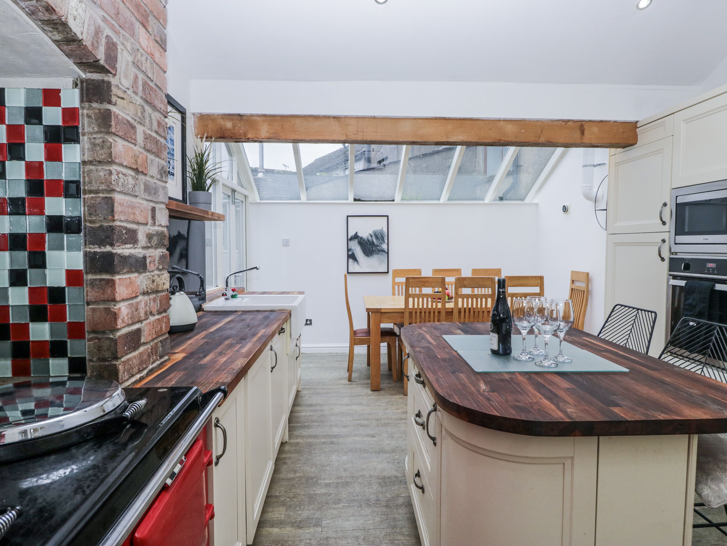A modern kitchen with a wooden island, a brick backsplash, and a dining area with wooden chairs and a table.