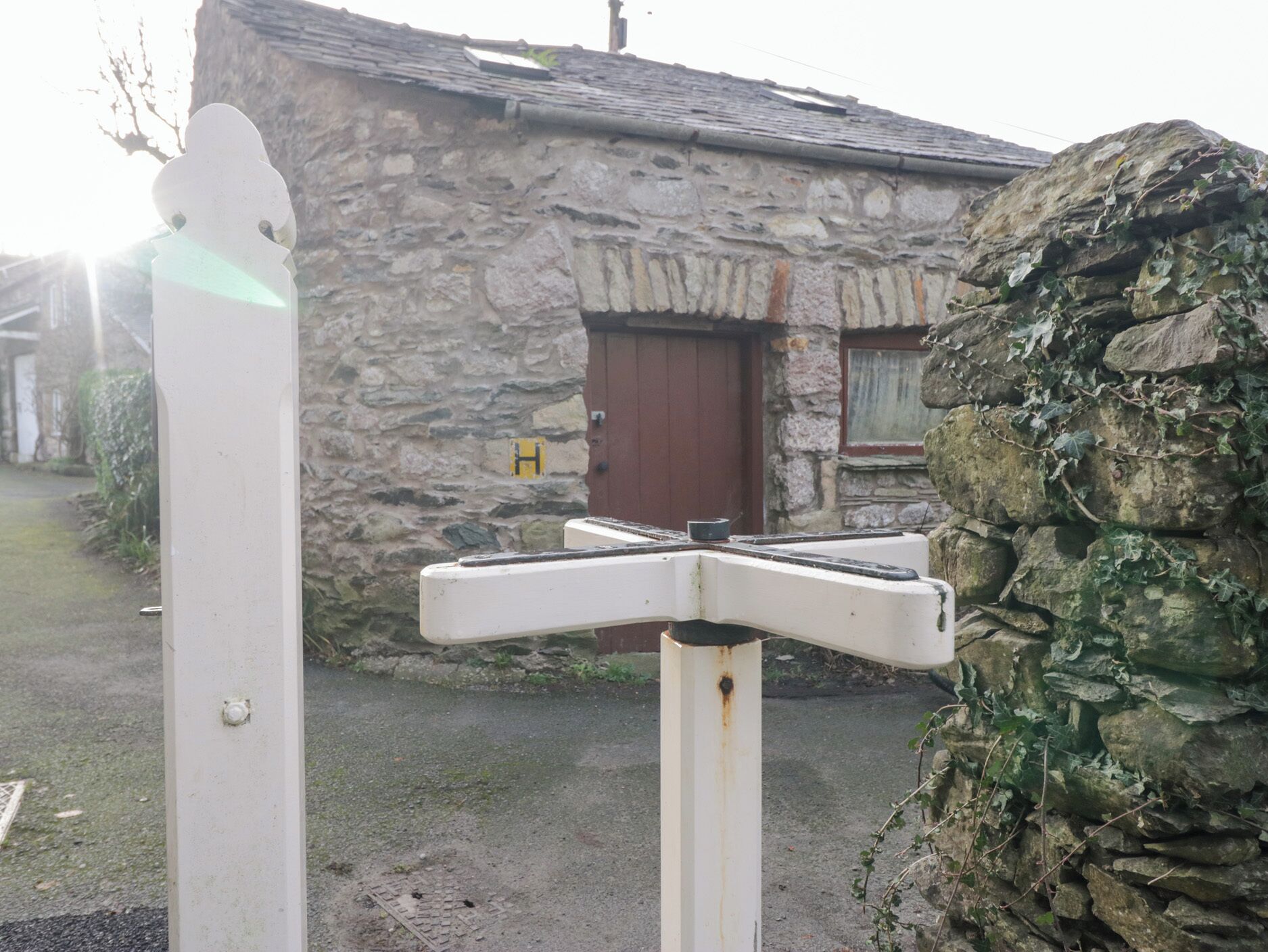 Ein Steinhaus mit roter Tür und einem weißen Wegweiser davor.