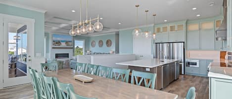 A modern kitchen with a central island, stainless steel appliances, and teal cabinetry.