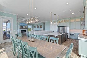 Een moderne keuken met een centraal eiland, roestvrijstalen apparatuur en kastjes in een blauwgroene kleur.