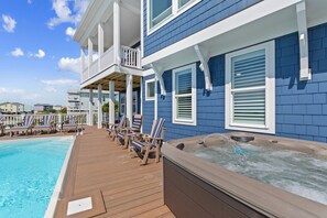 Ein Poolbereich mit Liegestühlen, einem Whirlpool und einer Holzterrasse.