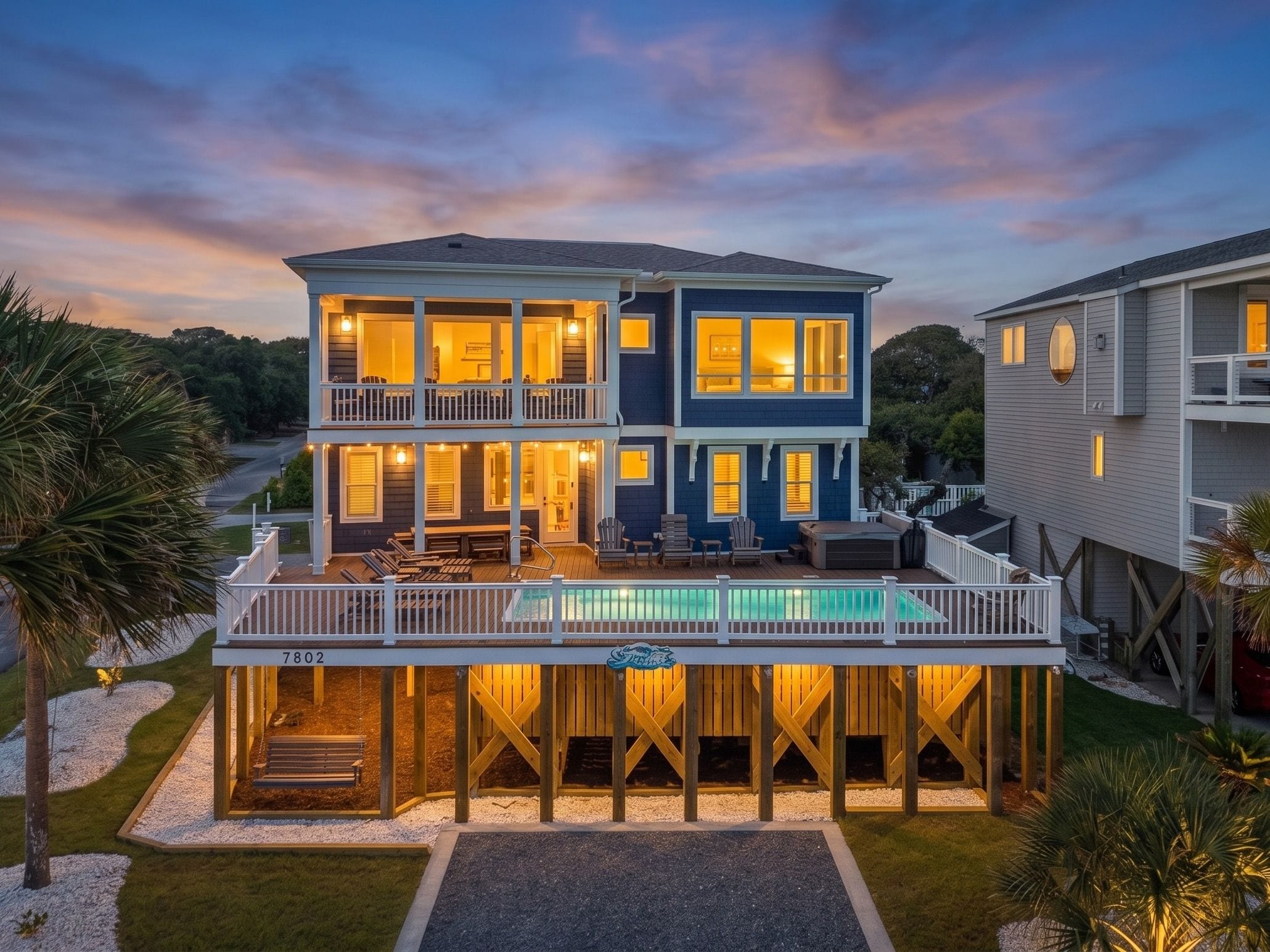Une maison à deux étages avec une piscine, une terrasse et le numéro « 7802 » inscrit sur la terrasse.
