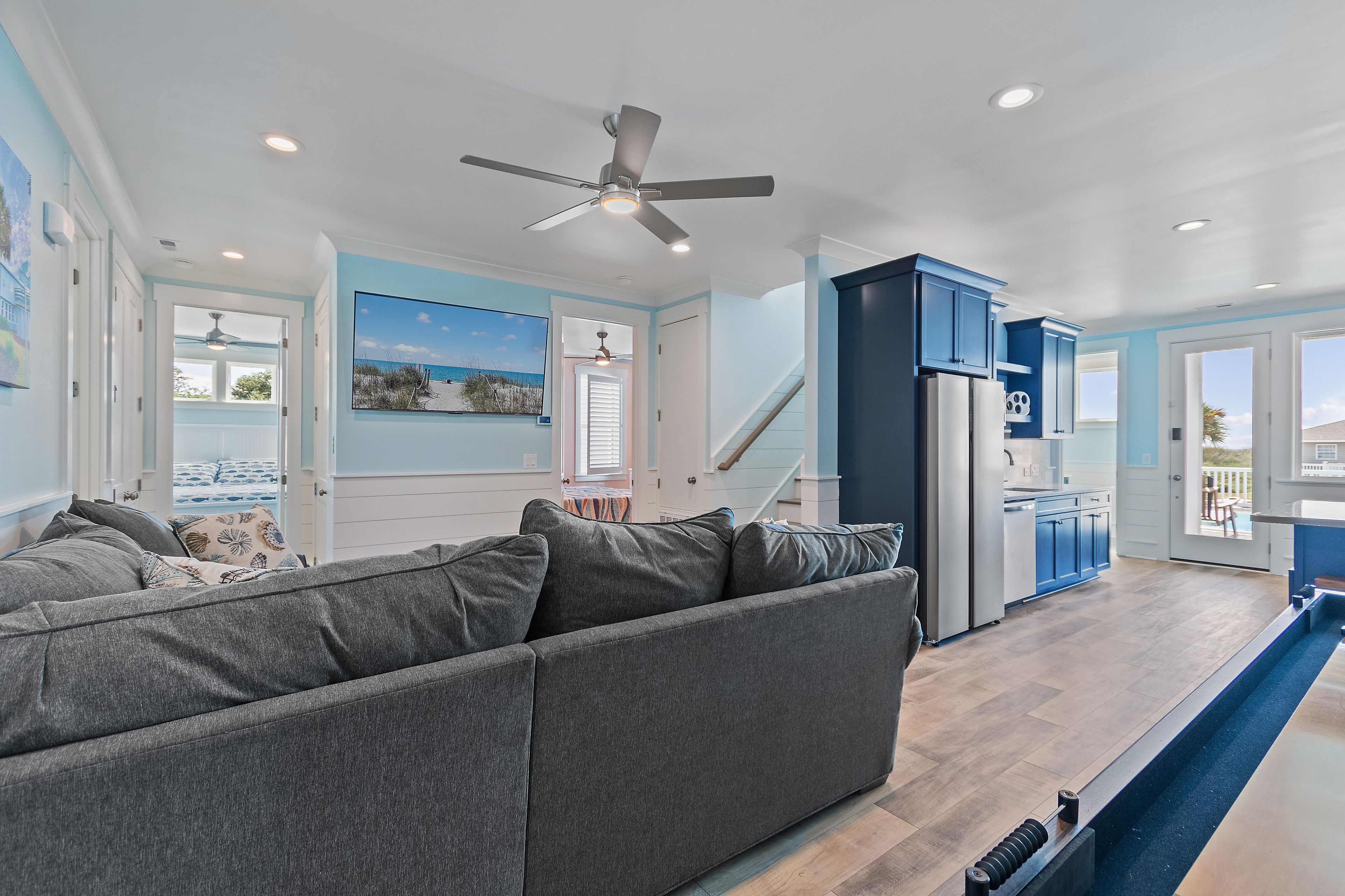 A modern kitchen with blue cabinets, a refrigerator, and a dining area with a table and chairs.