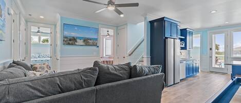 A modern kitchen with blue cabinets, a refrigerator, and a dining area with a table and chairs.