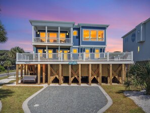 Une propriété de deux étages située en bord de mer, dotée d’une terrasse en bois et d’un balcon.