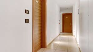 A corridor with wooden doors, white walls, and a tiled floor. - Room 'Camera Matrimoniale' with Mountain View, Wi-Fi and Air Conditioning (Mori)
