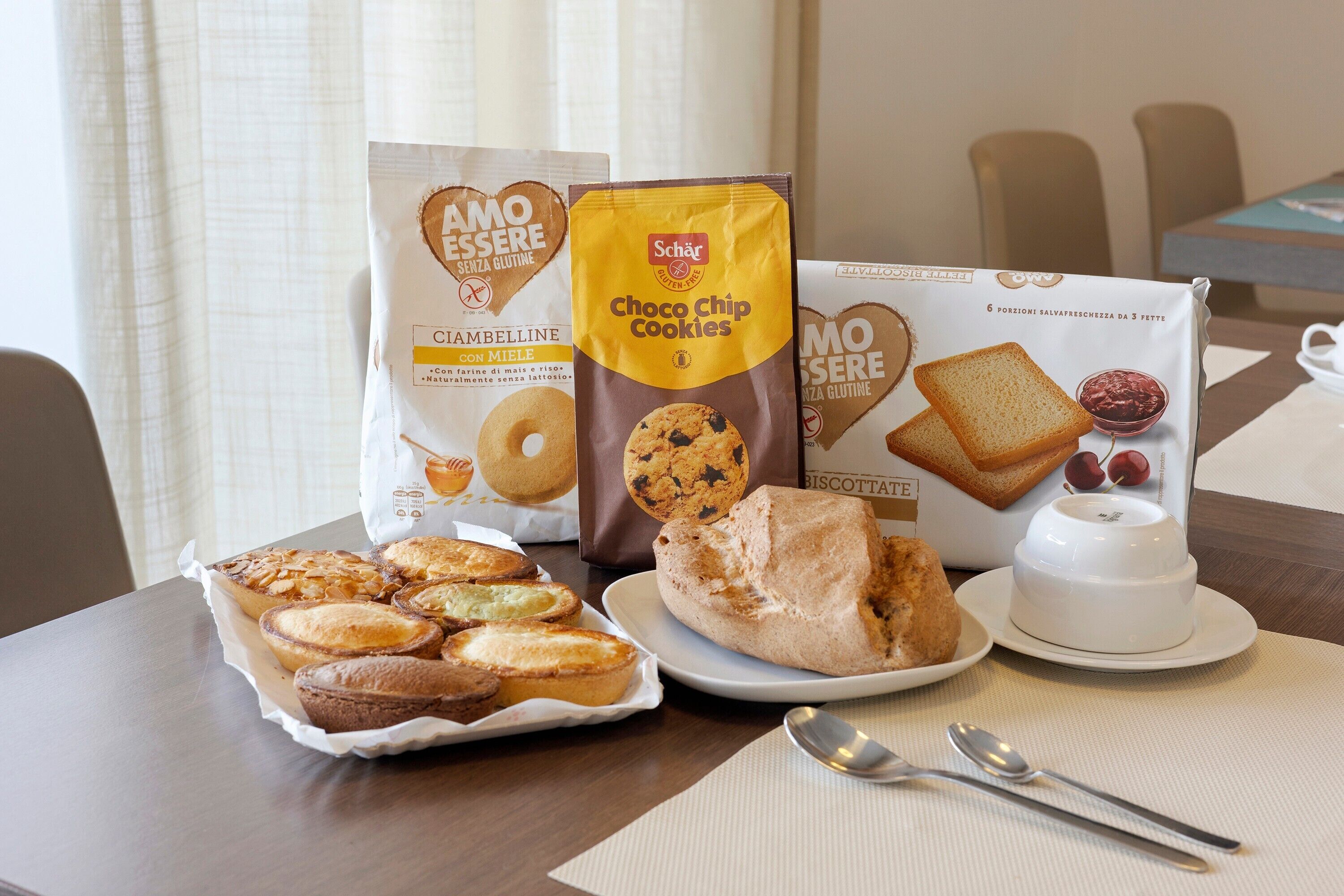 A table with various baked goods, including cookies and bread, and a white cup on a placemat.