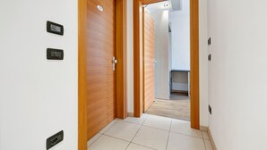 Ein Flur mit Holztüren, Fliesenboden und einem sichtbaren Badezimmer im Hintergrund.