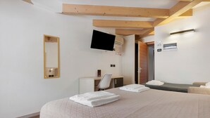 A hotel room with a bed, a desk, a chair, a TV, and a mirror.