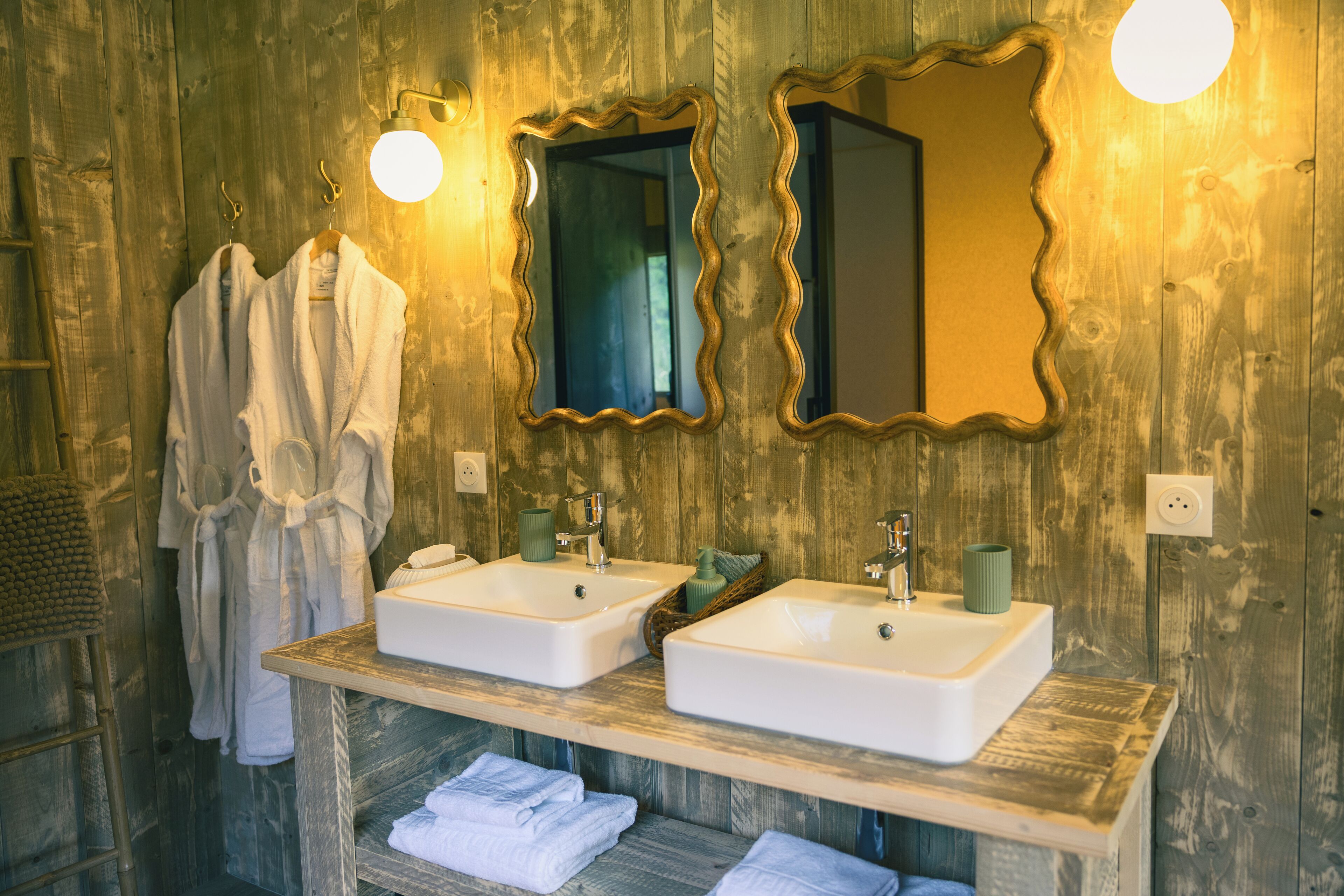 Une salle de bain avec deux lavabos, un miroir et un porte-serviettes.