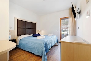 Une chambre à coucher avec un lit, une table de chevet et une vue sur l’extérieur.