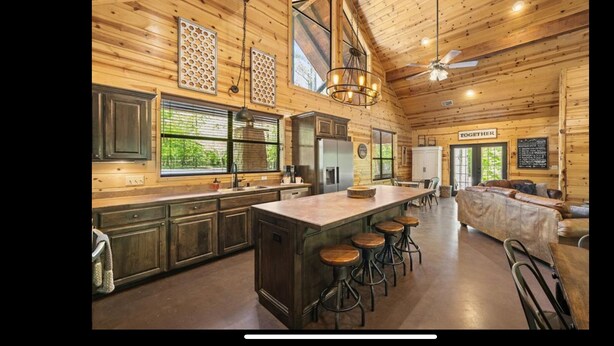 A spacious log cabin interior with a large kitchen, bar stools, and a cozy seating area. - Creekside Luxury Cabin w/ Hot Tub • Sleeps 12 (Broken Bow)