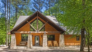 A log cabin with a stone foundation, a pitched roof, and a welcoming entrance. - Creekside Luxury Cabin w/ Hot Tub • Sleeps 12 (Broken Bow)