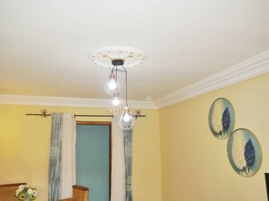 Una habitación con una lámpara en el techo, una puerta y dos adornos en las paredes.