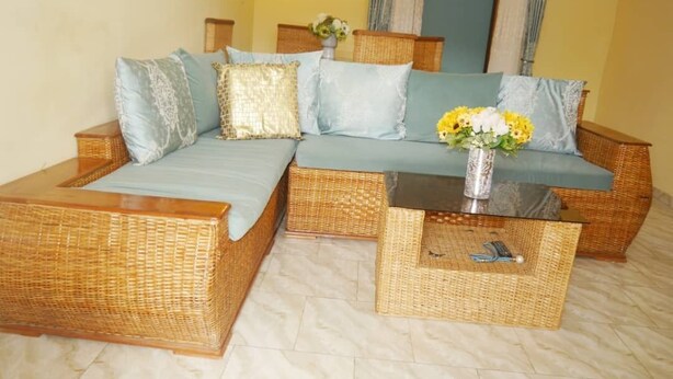 Una habitación con un amplio sofá modular, una pequeña mesa de centro y un jarrón con flores.