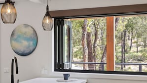 A modern kitchen with a large window, a sink, and pendant lights.