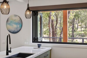 A modern kitchen with a large window, a sink, and pendant lights.