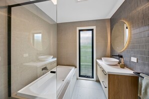 Un bagno moderno con una vasca, un lavandino e uno specchio.