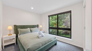 A bedroom with a large window, a bed, two bedside tables, and a lamp on each table.