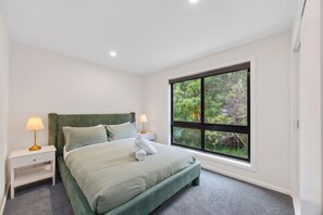 A bedroom with a large window, a bed, two bedside tables, and a lamp on each table.