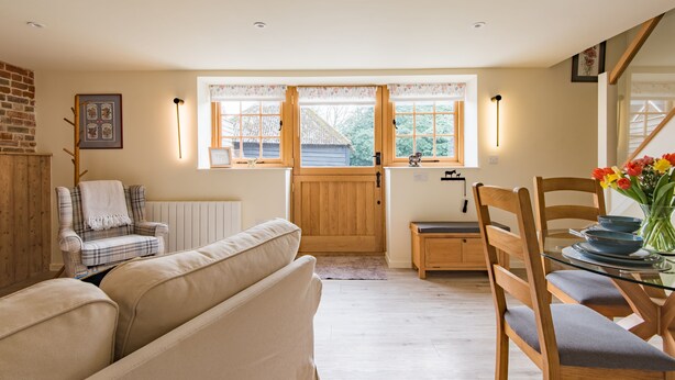 A cozy interior with a sofa, a plaid armchair, a dining table with chairs, and a window with a view of the outside. - The Stable, Preston, Kent (Preston)