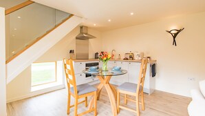 A modern kitchen with a glass dining table, wooden chairs, and a view of the outdoors. - The Stable, Preston, Kent (Preston)