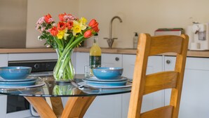 A kitchen with a round glass table, blue bowls, a vase with flowers, and a wooden chair. - The Stable, Preston, Kent (Preston)